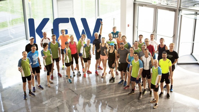 Betriebssportgruppe Triathlon mit vielen KfW Mitarbeitenden, die sportlicher Kleidung zum Joggen bereit stehen