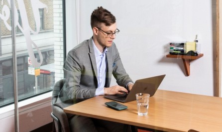 junger Mann sitzt mit Laptop an einem Tisch