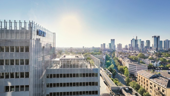 Drone image of the KfW location in Frankfurt. KfW's main building in the foreground left, the skyline in the background right. The sky is cloudless, the sun is shining.