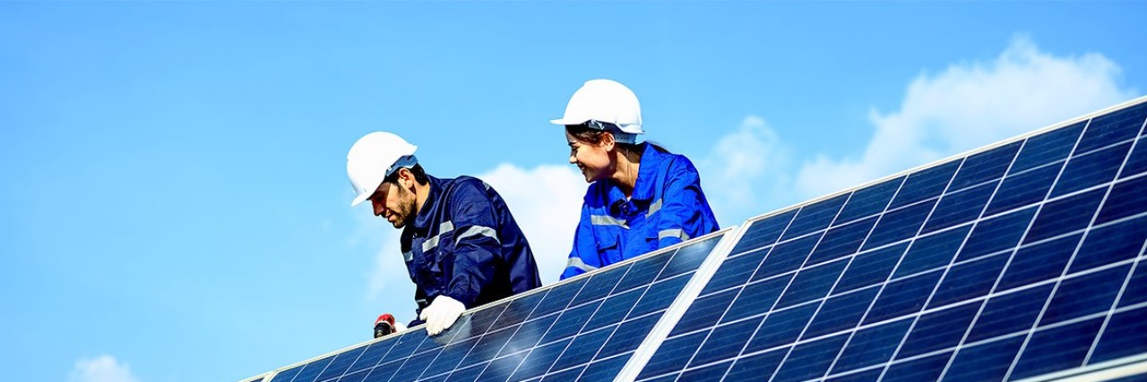 Eine Handwerkerin und ein Handwerker installieren Solarpanele