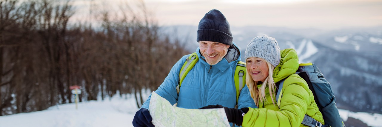 Älteres Paar mit Wanderkarte in einer Winterlandschaft