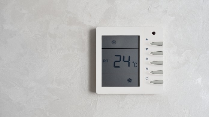 Temperaturregler mit Bildschirm hängt an der Wand und zeigt 24 Grad Celsius an.