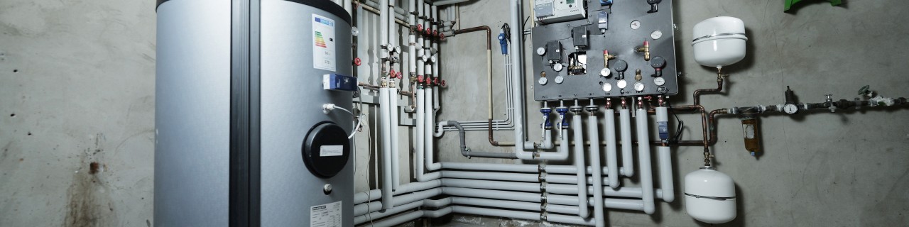 Fernwärmenetzanschluss mit Rohrleitungssystem im Heizraum eines Gebäudes.