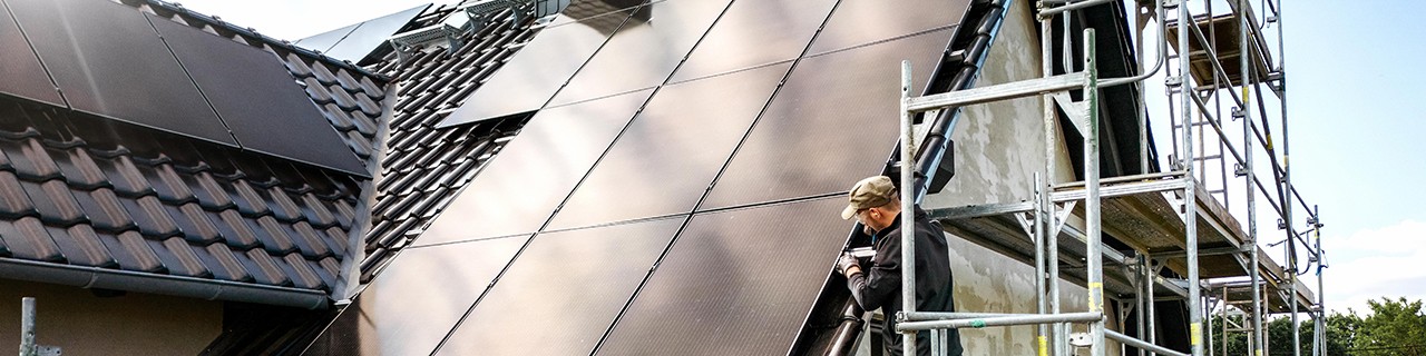 Ein Handwerker auf dem Gerüst vom Neubau eines klimafreundlichen Hauses mit Solardach