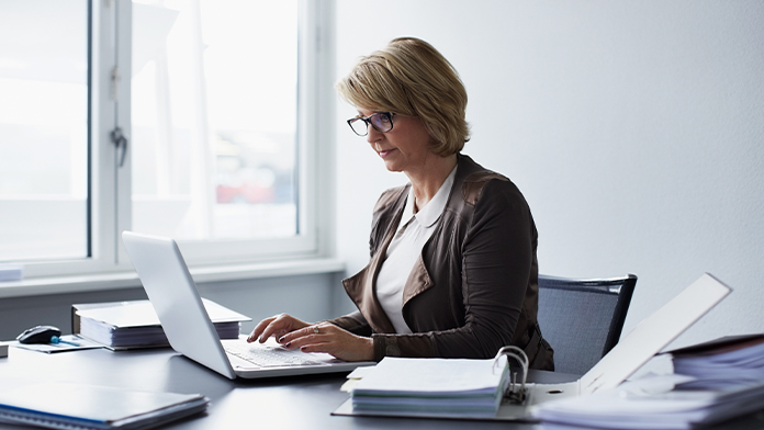 eine Frau sitzt und arbeitet am Schreibtisch