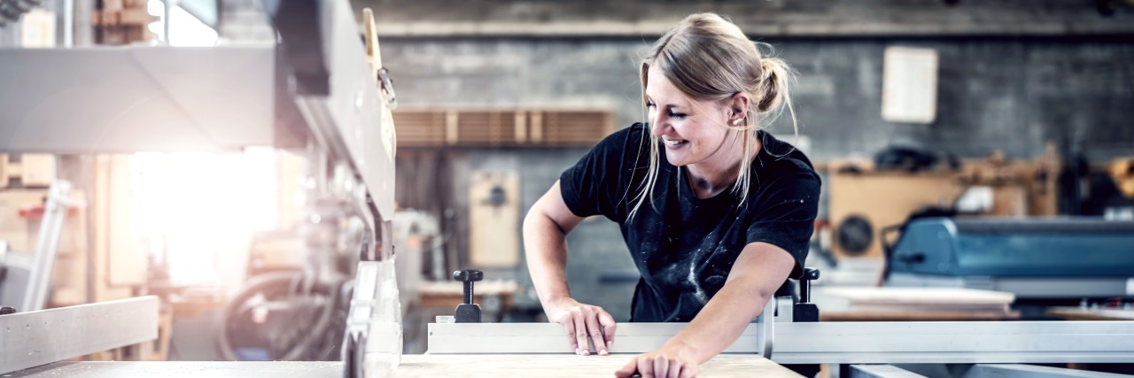 Einer blonde Frau arbeitet in einer Schreinerwerkstatt