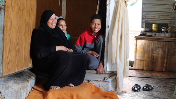 Frau sitzt mit zwei Kindern in einer Flüchlingsunterkunft in Za'atari