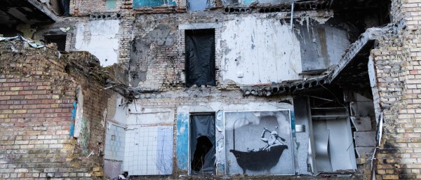 Ein von russischen Raketenangriff zerstörtes Wohnhaus in Kyiv mit Street-Art-Graffiti von Banksy